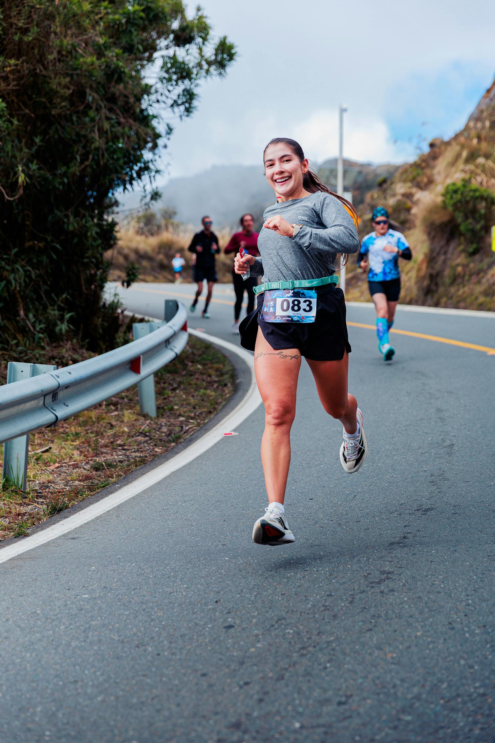 A cheerful runner participates in a mountain road marathon, displaying energy and determination.